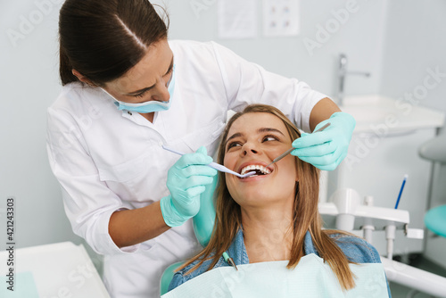 Woman sitting in medical chair while dentist fixing her teeth