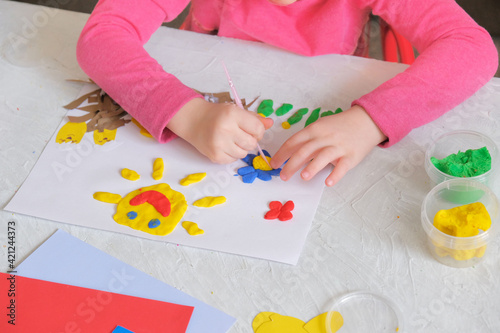 Child making spring card from colorful paper and clay. Handmade. Project of children's creativity, handicrafts, crafts for kids.