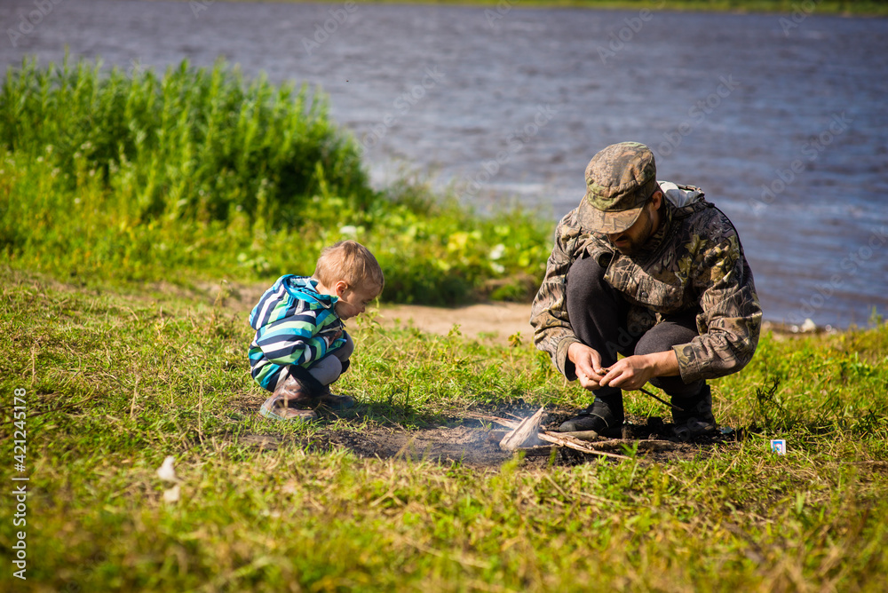 boy and his dad make a fire, selective focus 