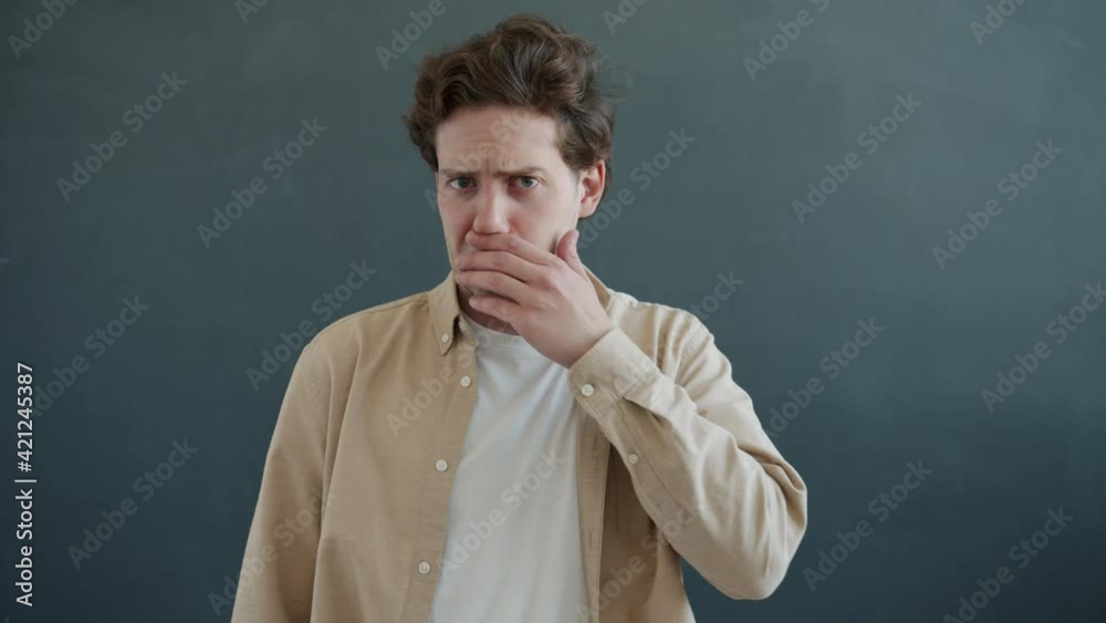 Portrait of disgusted young man wrinkling nose and showing no gesture standing on gray background. Negative attitude and human emotions concept. Portrait of disgusted young man wrinkling nose and showing no gesture standing on gray background. Negative attitude and human emotions concept.