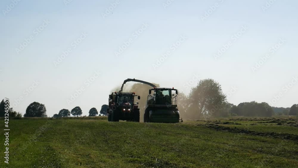 Agricultural harvester and tractor during some harvesting work Agricultural harvester and tractor during some harvesting work