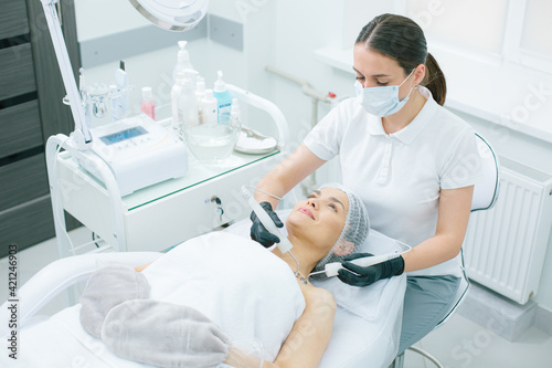 Experienced cosmetologist using metal prongs for micro current therapy