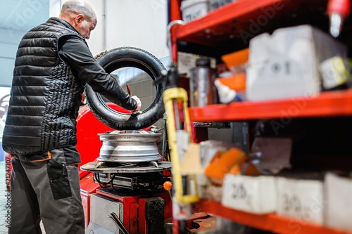 Mechanic at a car repair shop fitting a new tire on a vehicle rim