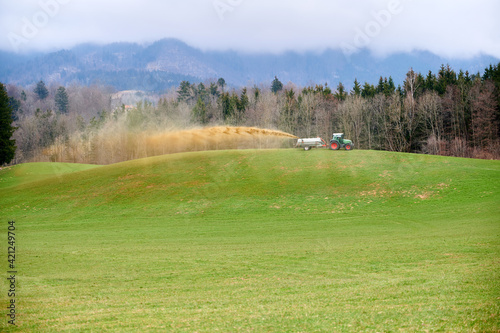 A farmer with a large tractor spreading liquid manure on grassland
