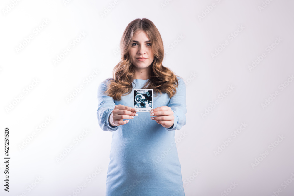 Portrait of a pregnant girl with an ultrasound scan in her hands in the studio on a white background Portrait of a pregnant girl with an ultrasound scan in her hands in the studio on a white background