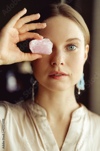 Young european girl holding a gemstone in hand in front of her. Looking towards the camera. Mystical woman..