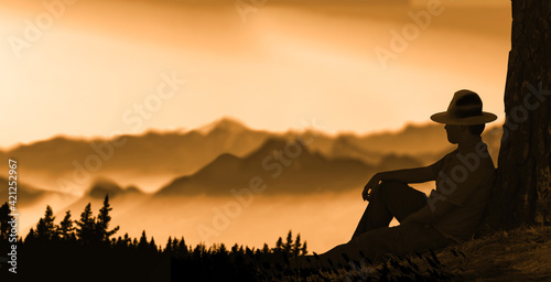 men wear hat leaning on tree trunk and relaxing while sitting on the grass in evening.