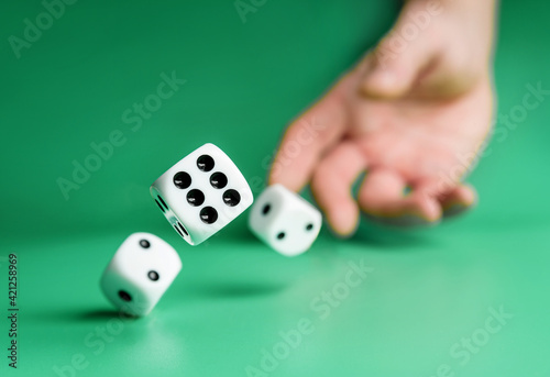 Hand throws dice on a green background with selective focus. photo