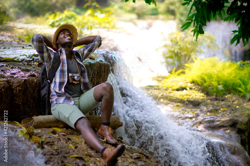 Fototapeta Naklejka Na Ścianę i Meble -  African traveler man sitting and relaxing freedom with waterfall