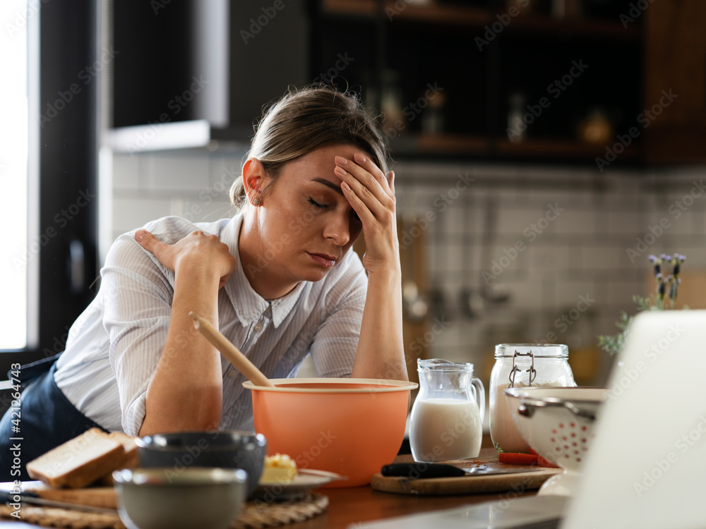 Young woman cooking in the kitchen. Beautiful woman watching movie on laptop while cooking Young woman cooking in the kitchen. Beautiful woman watching movie on laptop while cooking