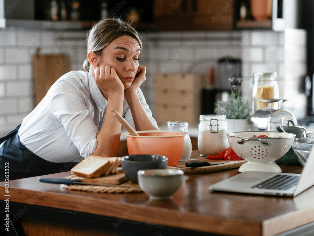 Young woman cooking in the kitchen. Beautiful woman watching movie on laptop while cooking Young woman cooking in the kitchen. Beautiful woman watching movie on laptop while cooking