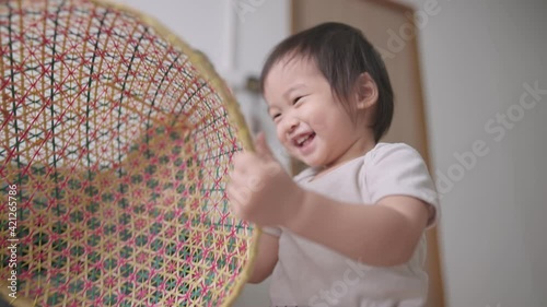 A little cute active 2years old female baby playing with asia traditional wooden dish cover by circling it around and put it covered happily on her head, ignoring plains, Cheerfulness in childhood photo
