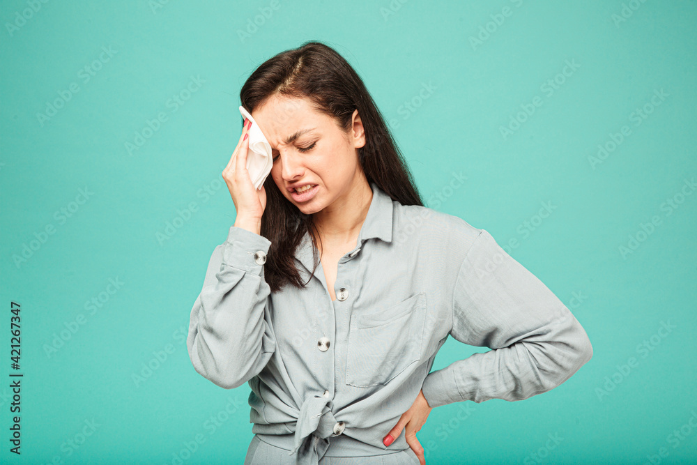 Photo of irritating female looks like she has headache. Wears grey shirt, isolated turquoise color background Photo of irritating female looks like she has headache. Wears grey shirt, isolated turquoise color background