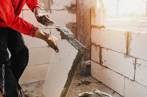 closeup hand of worker plastering cement on brick for building house photo