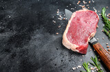 Raw New York steak or striploin with herbs. Black background. Top view. Copy space