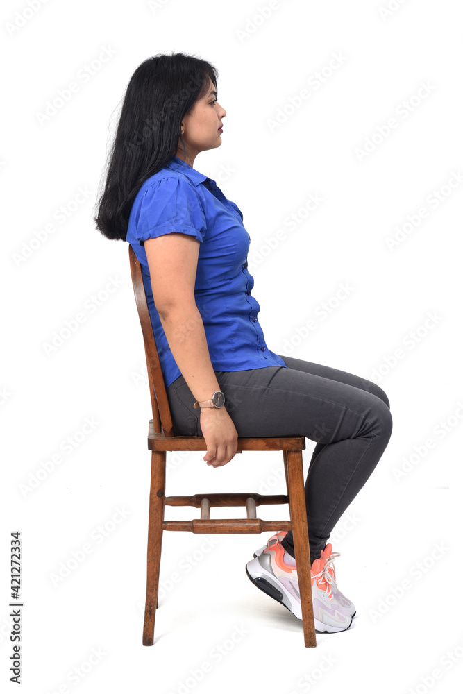 full portrait of a latin woman dressed in jeans sneakers and shirt sitting on chair on white background full portrait of a latin woman dressed in jeans sneakers and shirt sitting on chair on white background