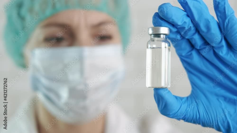 Human immunization and coronavirus. A woman show an ampoule with a coronavirus vaccine. A concept of popular immunization during coronavirus disease. Human immunization and coronavirus. A woman show an ampoule with a coronavirus vaccine. A concept of popular immunization during coronavirus disease.