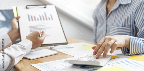 Business women are pressing a calculator to check together with male business partners, they are documenting company finances and verifying the accuracy of the information. Financial concept.