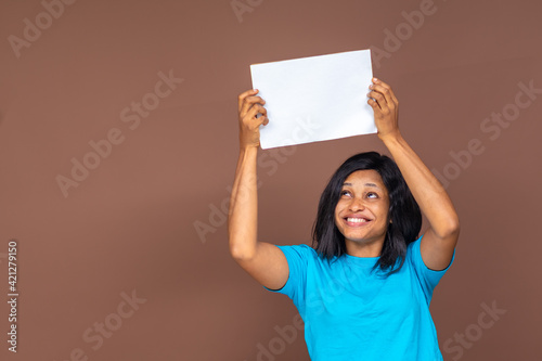 smiling pretty young black woman holding an empty sign above her head, advertising concept