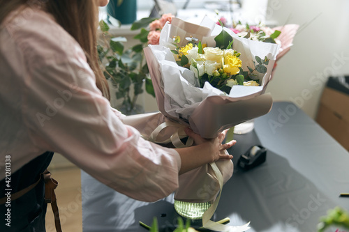 Nice and colorful bouqette of different flowers. Female florist hold it. She is in flower shop. Close up photo