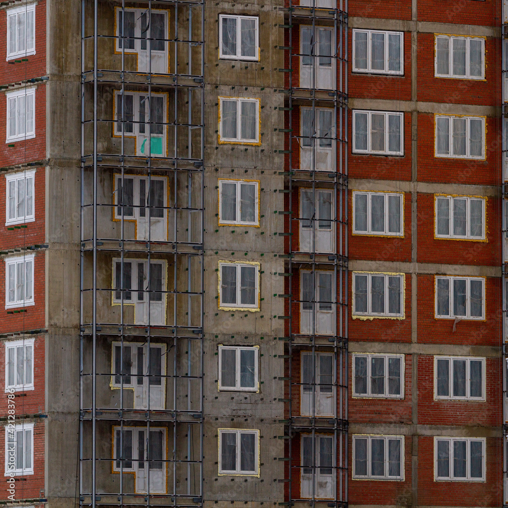 Fototapeta premium Construction of a residential multi-storey building. Windows, balconies. Concrete, brick walls. Metal structures.