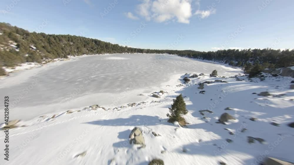 Exhilarating low level fpv drone flight across a frozen lake, snow and blue sky. Exhilarating low level fpv drone flight across a frozen lake, snow and blue sky.