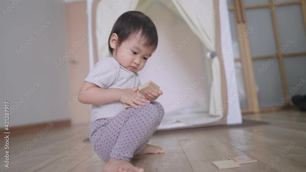 Playful female preschooler collecting wooden toys on living room floor, A helpful little baby girl helping mother clean up the room by collecting her own toys that scattered on the floor, childhood Playful female preschooler collecting wooden toys on living room floor, A helpful little baby girl helping mother clean up the room by collecting her own toys that scattered on the floor, childhood