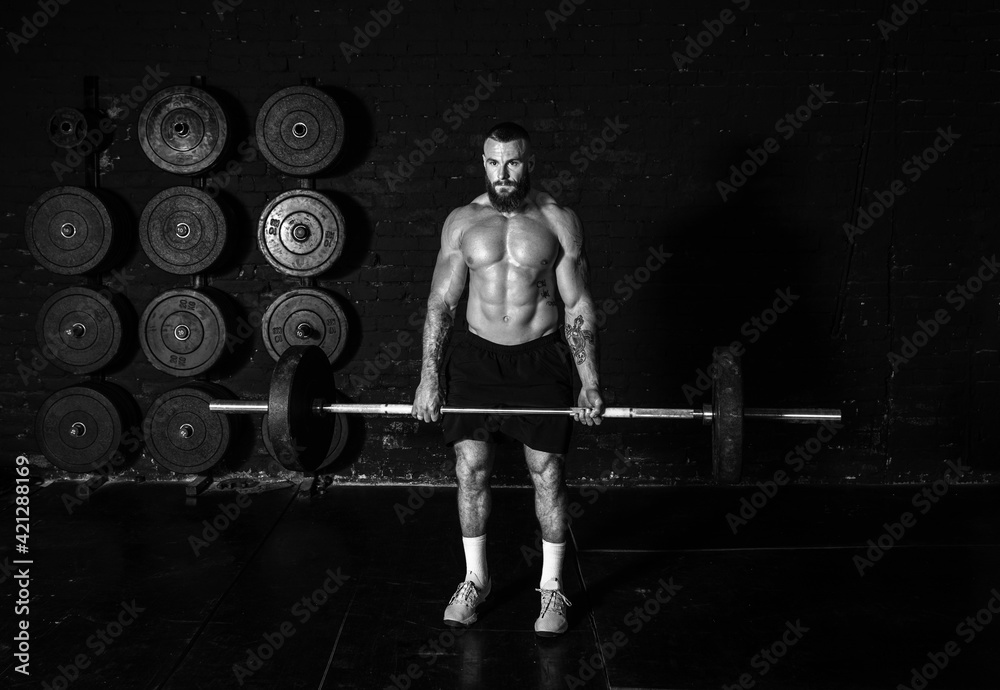 Fototapeta Young active sweaty strong muscular fit man with big muscles holding heavy barbell weight and starting hardcore weightlifting or deadlift workout cross training in the gym real people exercise