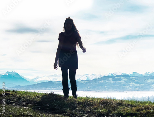 Junge Frau mit langen Haaren vor Bodenseepanorama im Gegenlicht