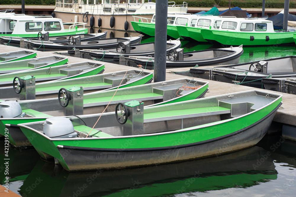 Many green motor powered boats for rent in small harbor in dutch canal. Popular way to spend a weekend in Netherlands.
