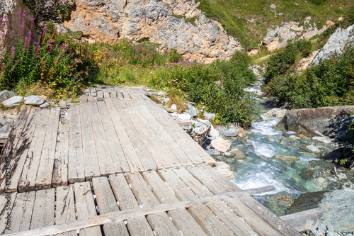 Mountain river and wood bridge in Vanoise national Park valley, French alps