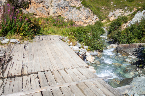 Mountain river and wood bridge in Vanoise national Park valley, French alps photo