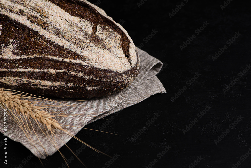 Artisan crusty dark rye bread on gray linen napkin. Copy space. Low key.