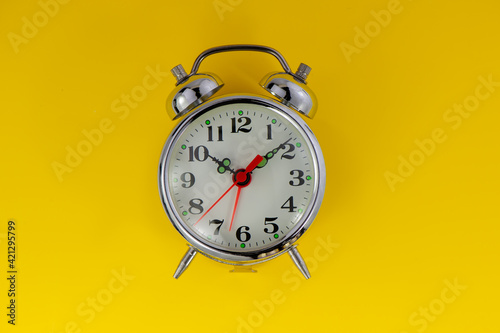 old mechanical alarm clock lies on a yellow background.