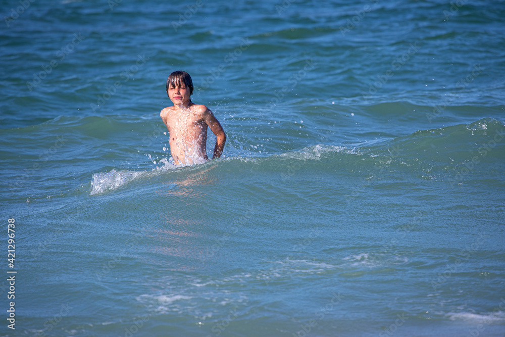 happy boy emerges from the sea with closed eyes, horizontal format