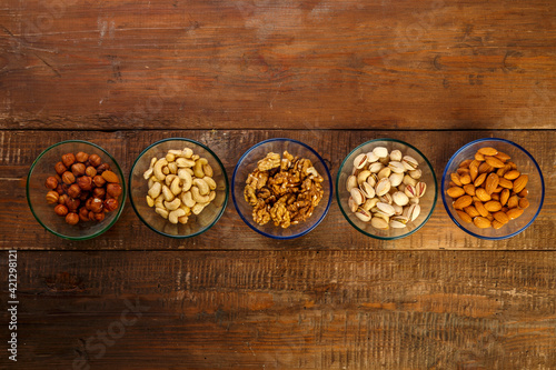 Assorted nuts in a glass bowl on a wooden table.