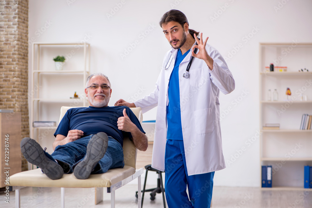 Obraz premium Old male patient visiting young male doctor chiropractor