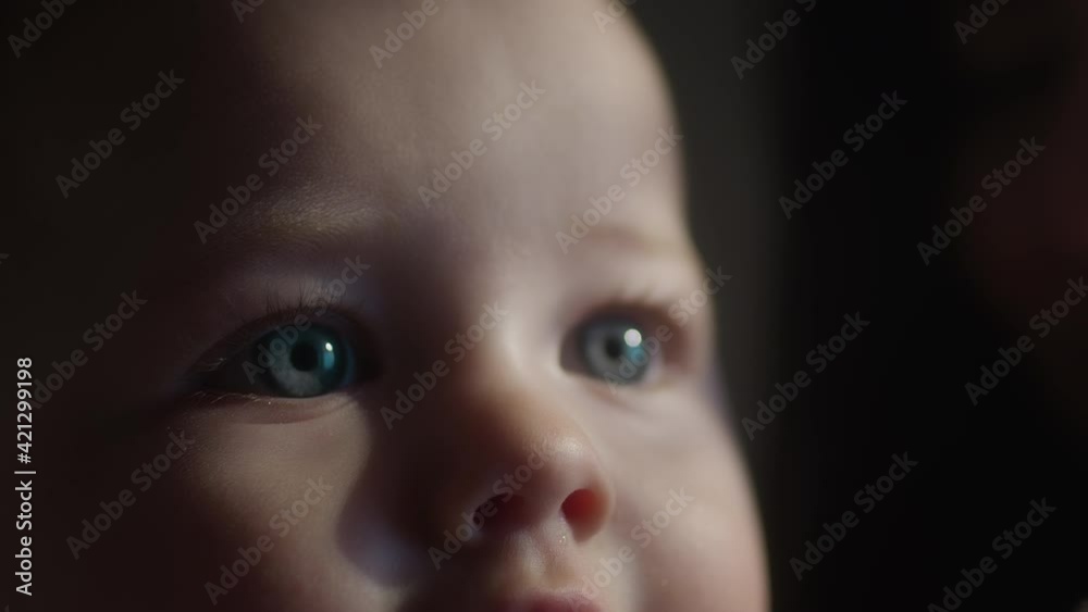 Cinematic close-up of a child's blue eyes. The child learns the world. Looks at the light from the window, the sun's rays. Home comfort, maternity leave. Portrait of a happy kid on a summer sunny day Cinematic close-up of a child's blue eyes. The child learns the world. Looks at the light from the window, the sun's rays. Home comfort, maternity leave. Portrait of a happy kid on a summer sunny day