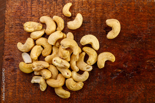 Cashew nuts scattered on a square board on a wooden table.