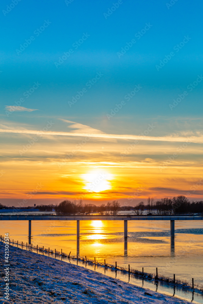 Fototapeta premium Sunset landscape with frozen floodplains in The Netherlands