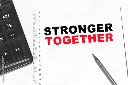 Text STRONGER TOGETHER on paper card, Pencils on table - business, banking, finance and investment concept.