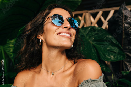 Happy ethnic woman enjoying sunny day in exotic garden