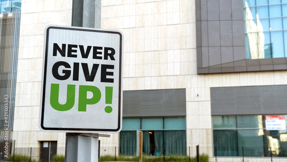 Never Give Up sign in a downtown city setting