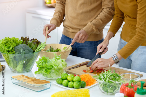 Young couple preparing a meal chopping vegetables in kitchen at home, healthy lifestyle.
