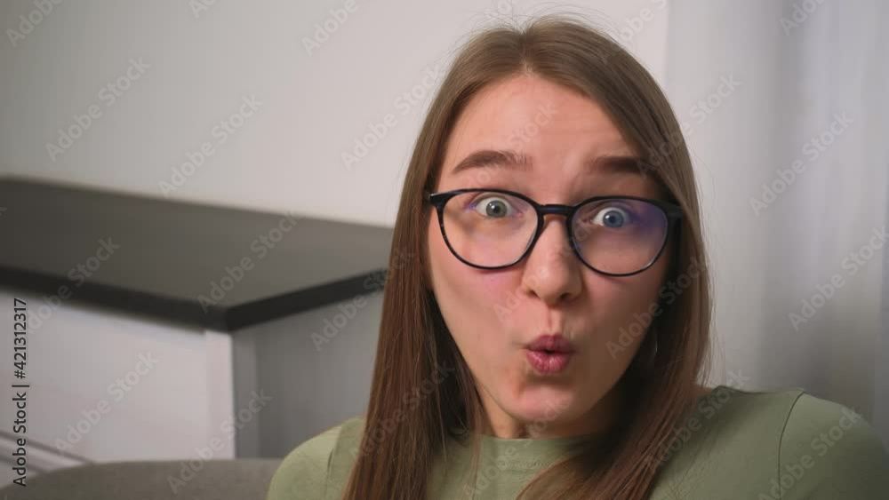 Closeup portrait of surprised smiling excited young woman in glasses opening her mouth in amazement, shouting Wow on home office Closeup portrait of surprised smiling excited young woman in glasses opening her mouth in amazement, shouting Wow on home office