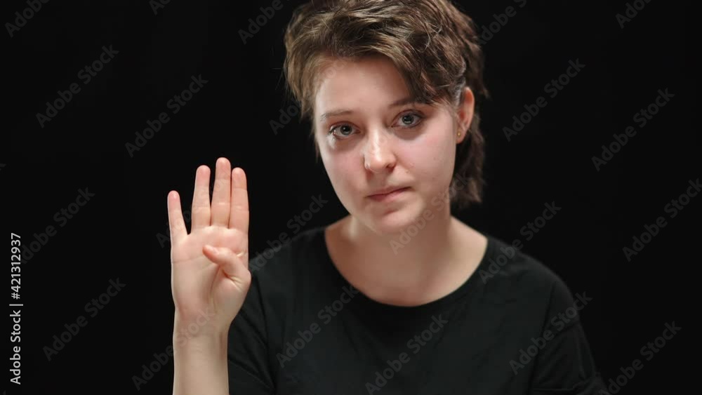 Close-up portrait of scared abused young woman looking around and showing sign to help palm at camera with tuck thumb. Desperate Caucasian lady at black background. Tyranny and domestic violence. Close-up portrait of scared abused young woman looking around and showing sign to help palm at camera with tuck thumb. Desperate Caucasian lady at black background. Tyranny and domestic violence.