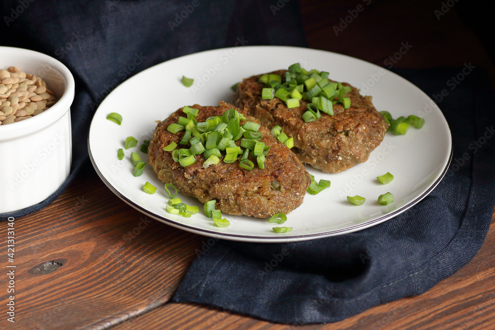 Lentil cutlets garnished with green onions and cucumber on rustic wooden table, closeup, vegetarian lenten eastern dish, healthy vegan food concept Lentil cutlets garnished with green onions and cucumber on rustic wooden table, closeup, vegetarian lenten eastern dish, healthy vegan food concept