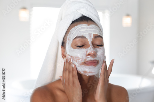 African american woman applying face mask in bathroom