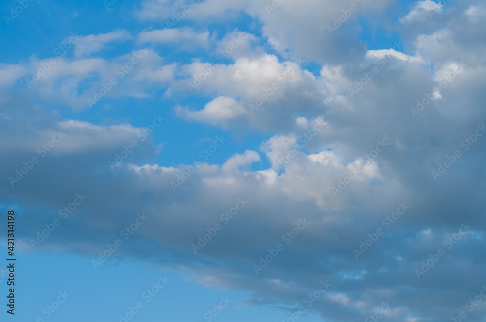 Bright blue sky with white fluffy clouds and bright sunlight.