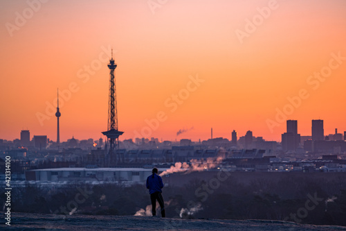 silhouette of a person on a hill above the city of berlin during sunset